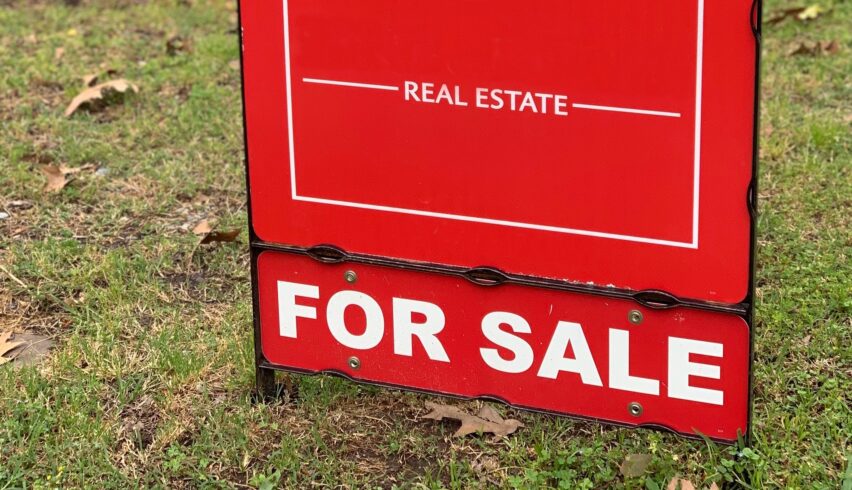 Red Real Estate For Sale sign at a neighborhood home.